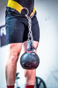 Sportler hat eine Kettlebell als Zusatzgewicht an einem Gürtel um die Hüfte hängen